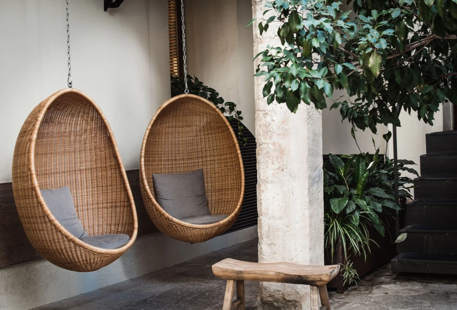 Hai chiếc ghế trứng đan mây treo ngoài trời tạo góc nghỉ ngơi thư giãn giữa vườn cây xanh mướt. | Thiết kế nội thất 24