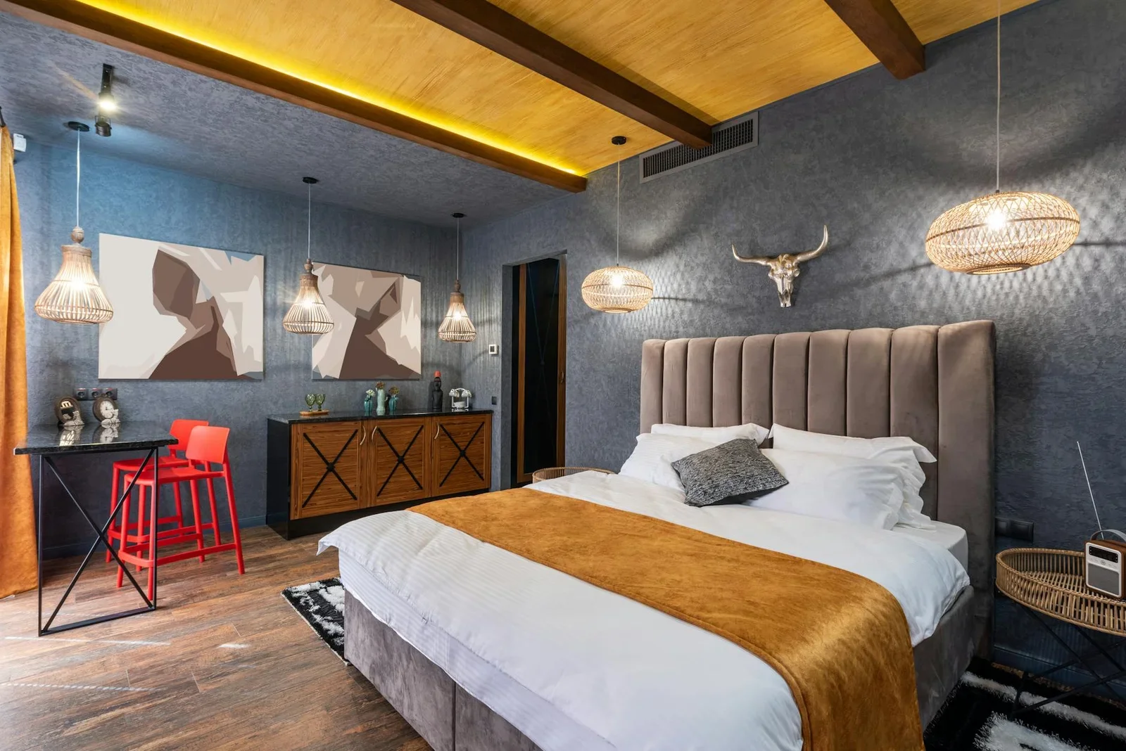 Giường nệm êm ái đặt dưới gạc nai trang trí, ánh sáng vàng ấm áp tôn lên những bức tranh nghệ thuật trên tường. | Thiết kế nội thất 24