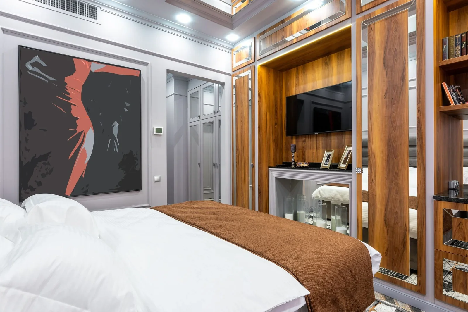 Giường ngủ hiện đại nằm giữa tranh nghệ thuật và kệ sách gọn gàng, được chiếu sáng hài hòa, tạo góc đọc sách và nghỉ ngơi lý tưởng. | Thiết kế nội thất 24