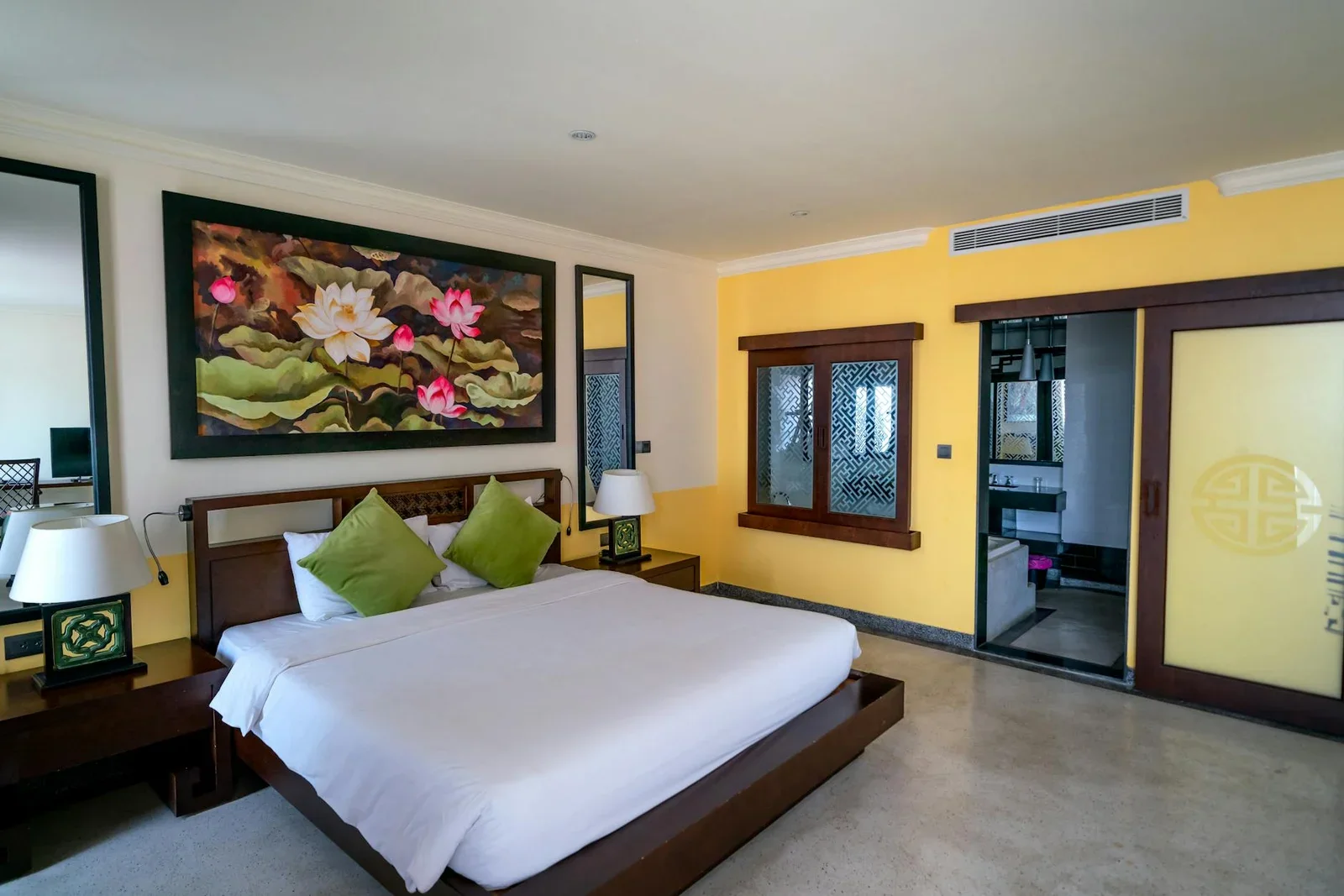 Phòng ngủ ấm cúng nổi bật với giường gỗ tự nhiên, tranh hoa rực rỡ và đèn bàn tỏa ánh sáng dịu dàng. | Thiết kế nội thất 24