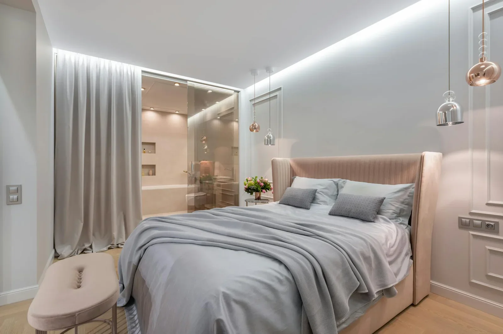 Giường êm ái cạnh ghế pouf và bàn nhỏ dưới đèn vàng, cửa kính rèm che thông sang khu vệ sinh tiện lợi cho ông bà. | Thiết kế nội thất 24