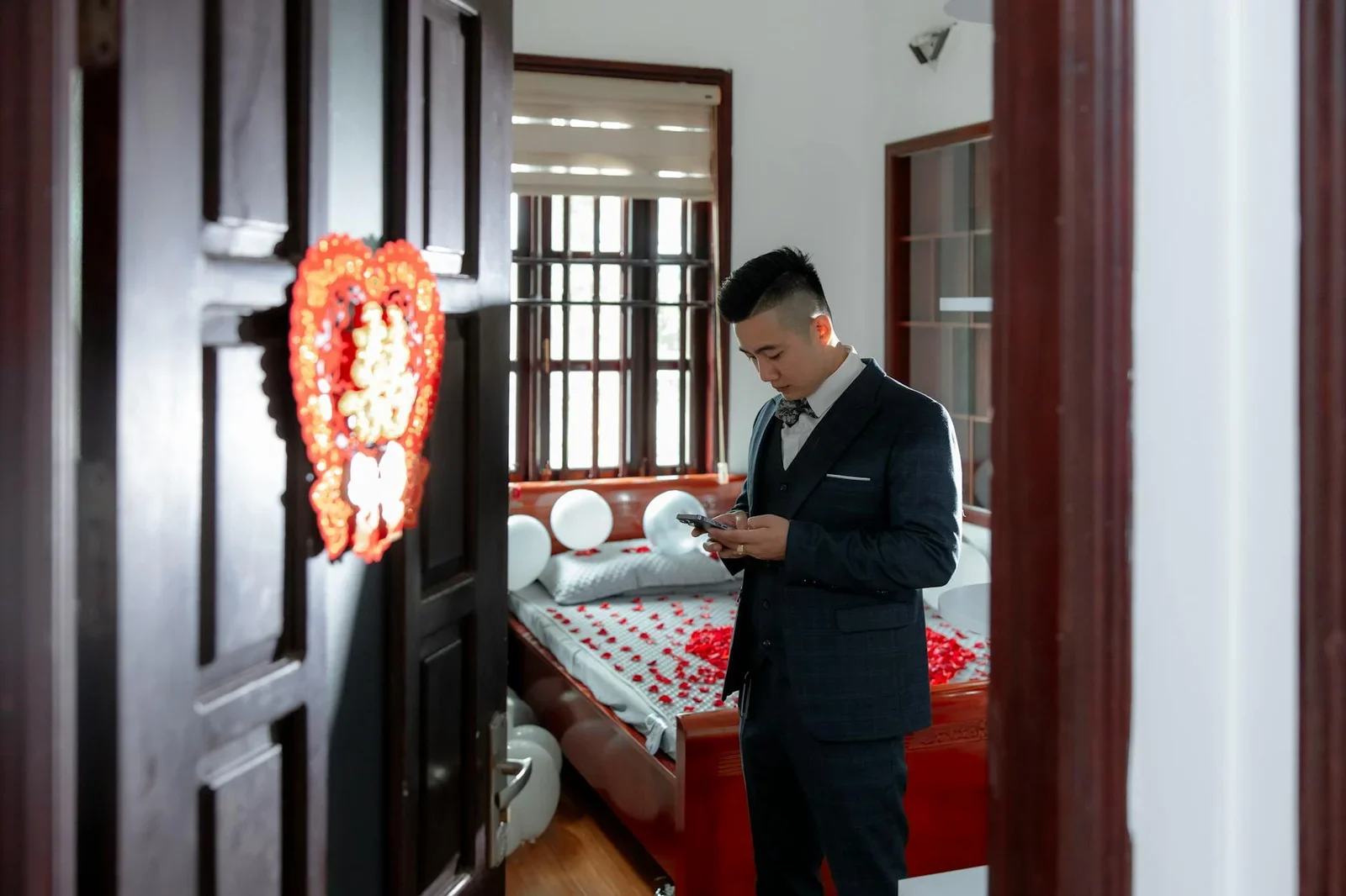 Không gian phòng ngủ lãng mạn với hoa hồng và bóng bay, nơi chú rể chỉn chu trang phục trong bầu không khí ấm áp. | Thiết kế nội thất 24