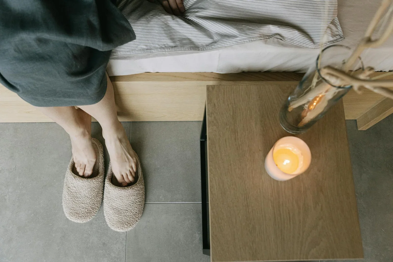 Khung cảnh phòng ngủ tĩnh lặng với dép đi nhà, bàn gỗ tự nhiên và ánh nến ấm áp khơi gợi cảm giác bình yên. | Thiết kế nội thất 24