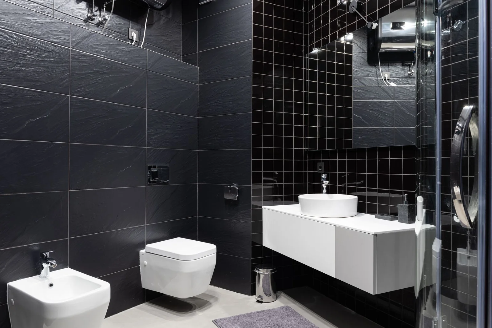 Phòng tắm hiện đại kết hợp chậu rửa và bệ xí đặt cạnh gương lớn, được ốp gạch đen bóng tạo điểm nhấn thẩm mỹ cao. | Thiết kế nội thất 24
