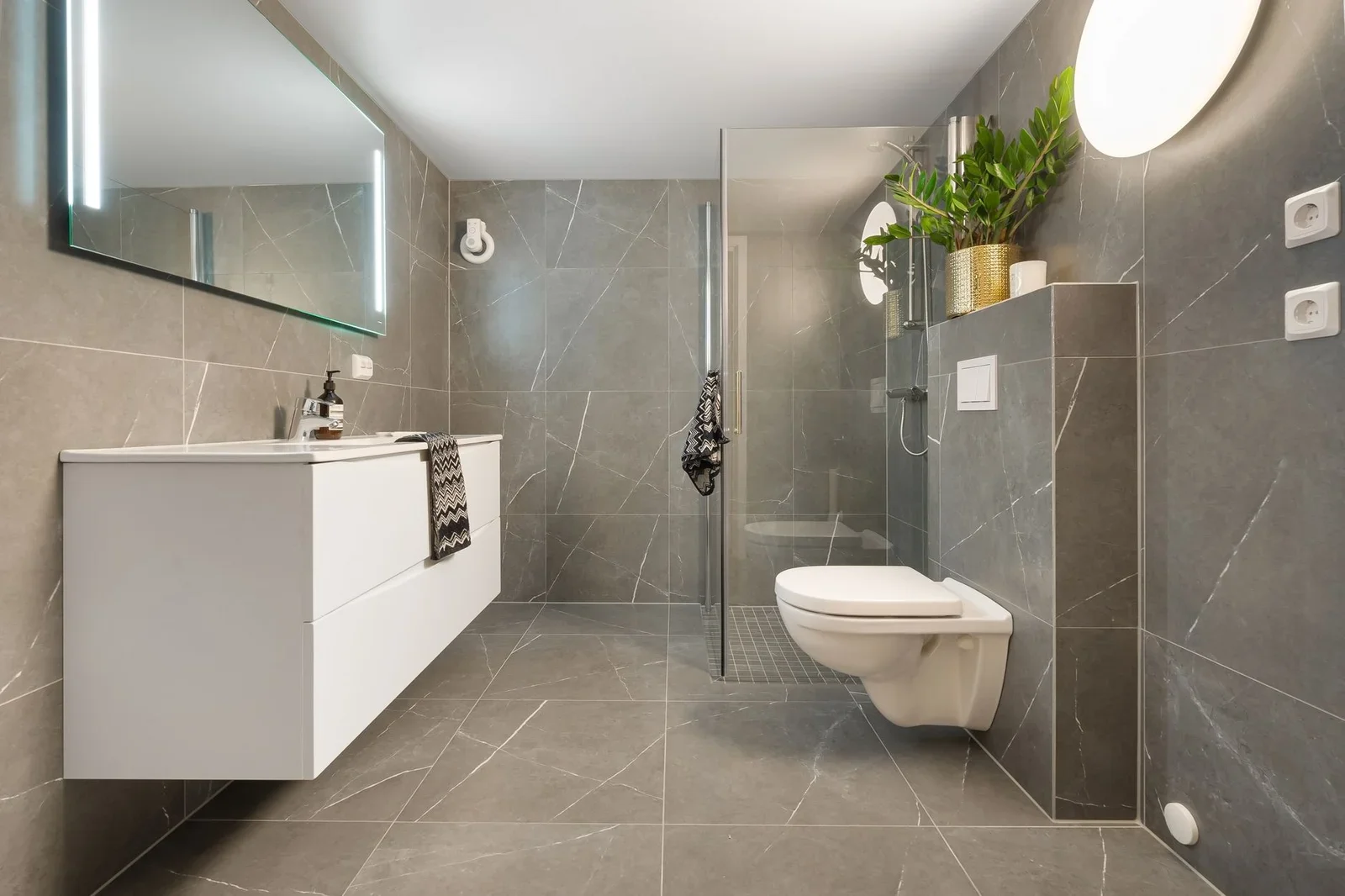 Stylish gray tiled bathroom featuring a shower, toilet, and  | Thiết kế nội thất 24