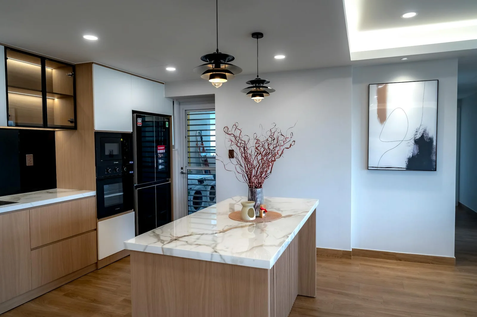 Phong cách tối giản thể hiện rõ qua quầy đảo đá cẩm thạch cùng hệ đèn thả trần tạo chiều sâu cho góc bếp nhỏ. | Thiết kế nội thất 24
