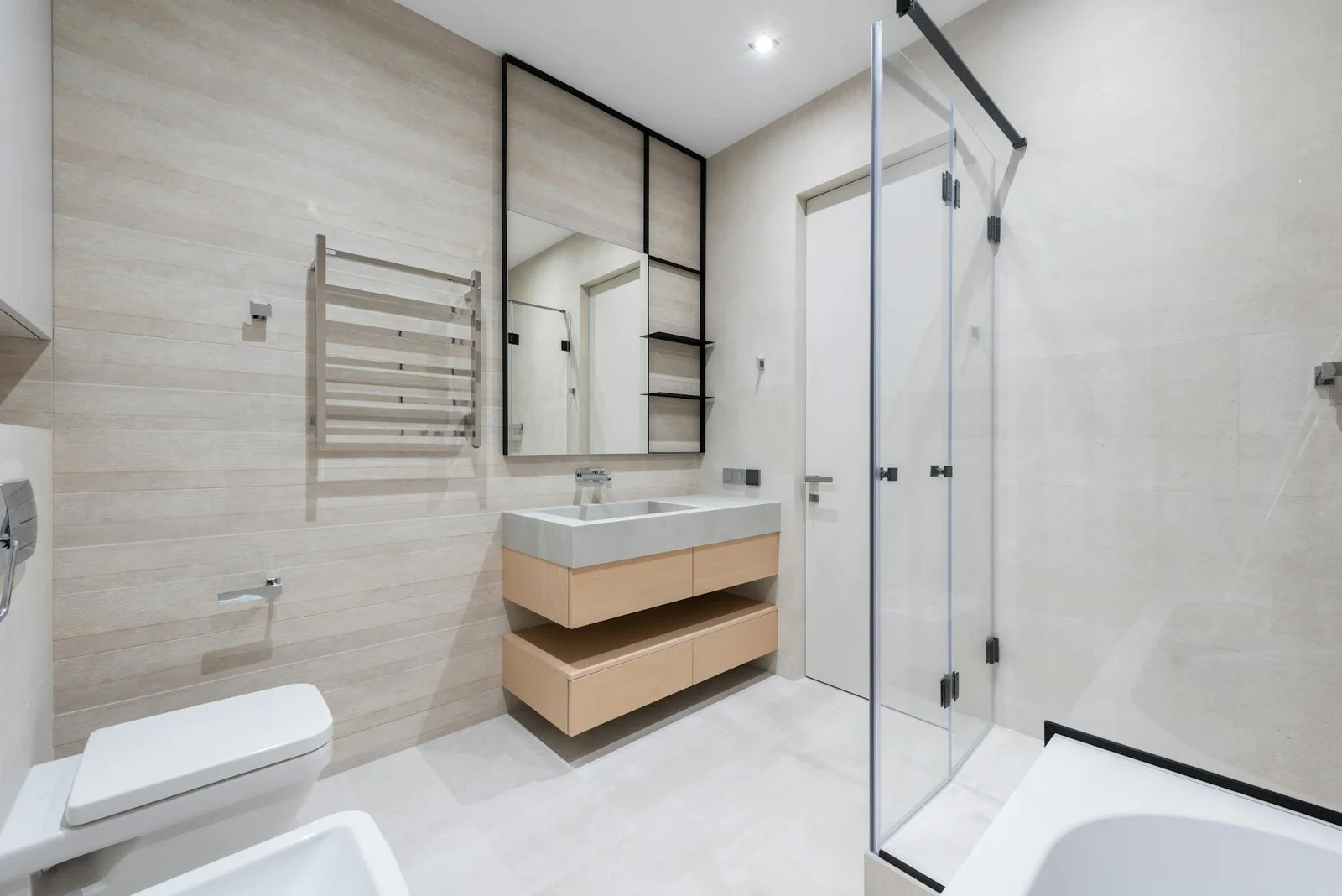 Nội thất phòng tắm sáng màu hiện đại bố trí bồn cầu và bồn bidet sát bồn tắm, chậu rửa đặt trên tủ dưới gương. | Thiết kế nội thất 24