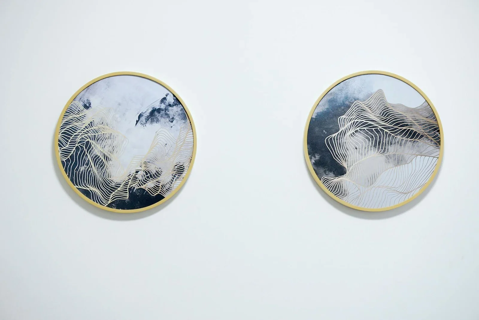 Two abstract circular paintings with gold frames on a white | Thiết kế nội thất 24