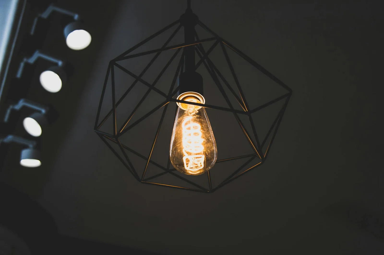 Bóng đèn dây tóc cổ điển phát sáng trong lồng sắt hình học, mang đến điểm nhấn hiện đại cho không gian nội thất. | Thiết kế nội thất 24