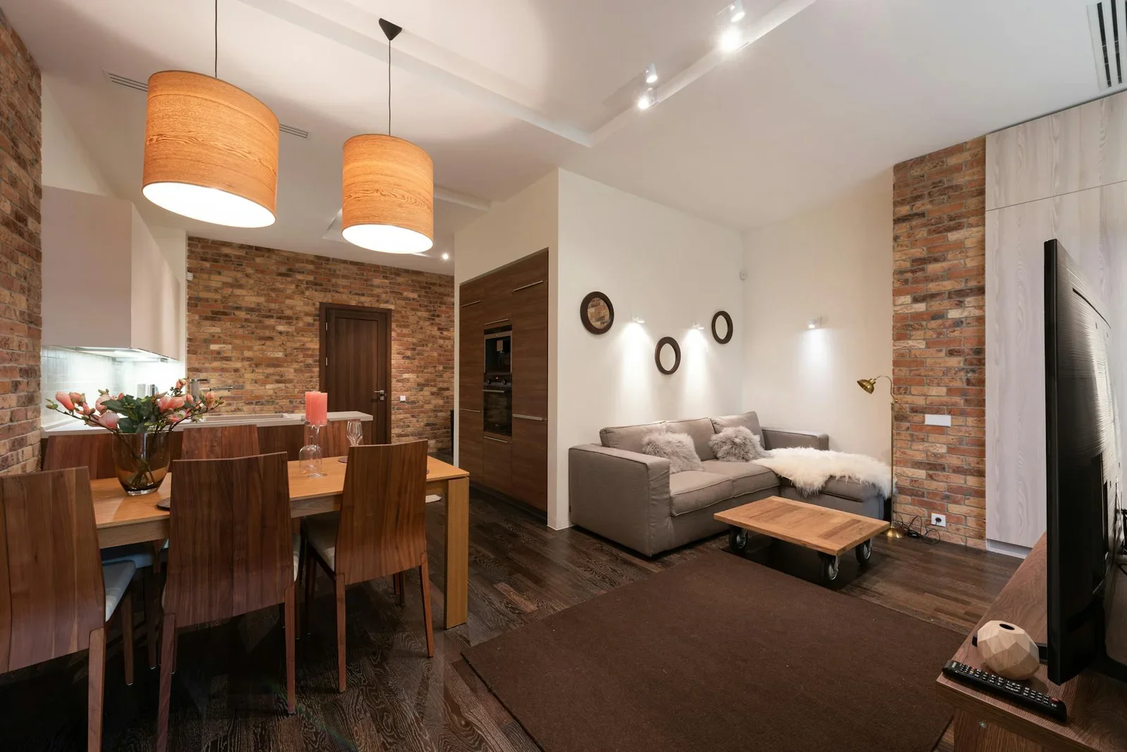 Phòng khách hiện đại tích hợp bàn ăn trang trí nến hoa, tủ kệ gọn gàng cùng sofa êm ái và tivi giải trí. | Thiết kế nội thất 24