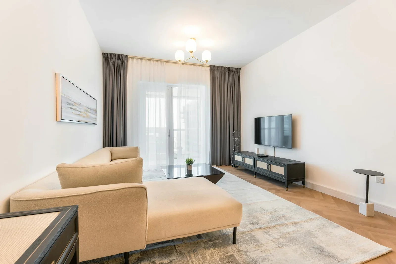 Phòng khách tràn ngập ánh sáng ấm áp, phối hợp hài hòa giữa sofa màu be, tivi màn hình phẳng và decor tinh tế. | Thiết kế nội thất 24