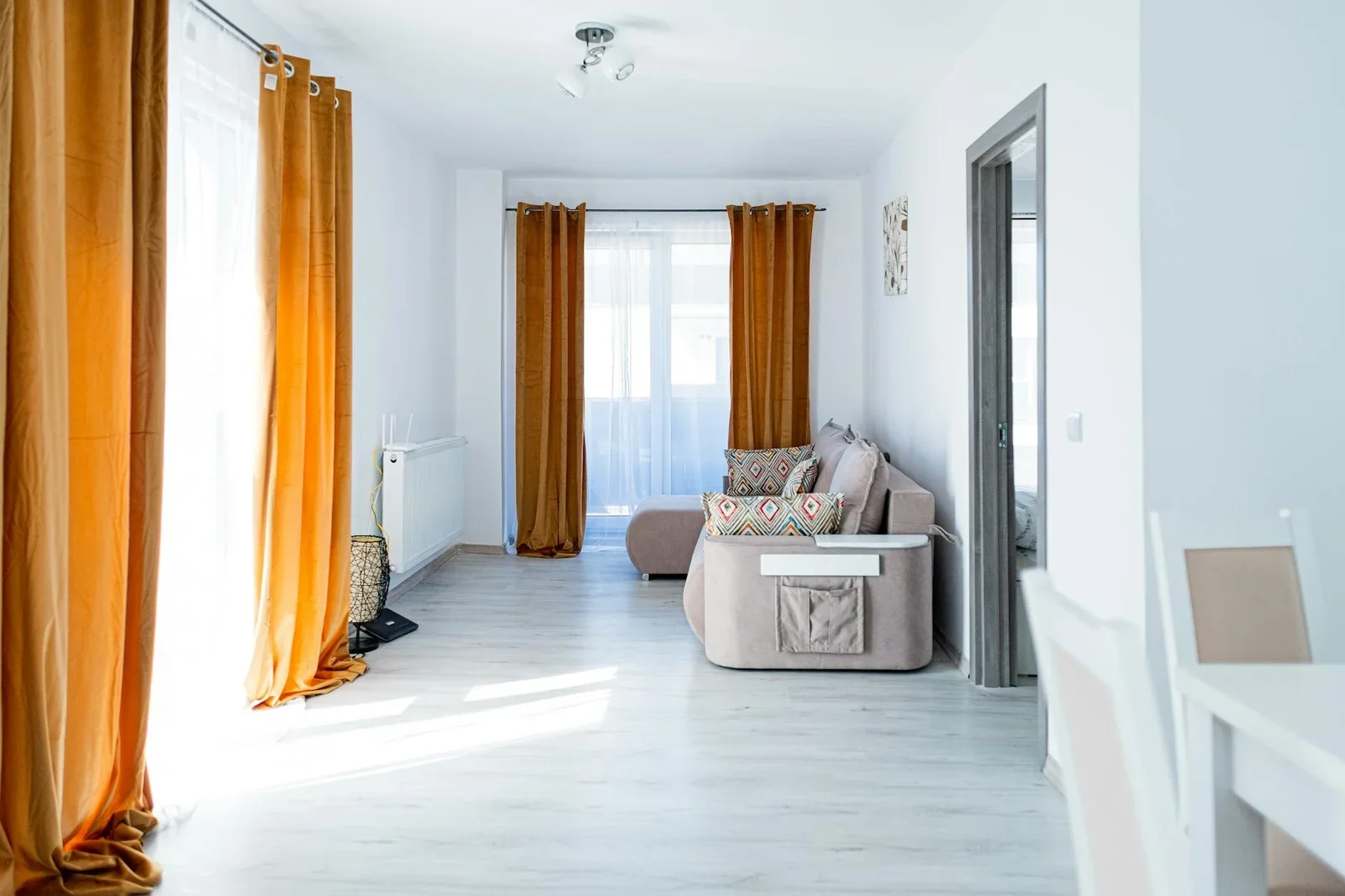 Rèm cửa cam nổi bật kết hợp ghế sofa be trang nhã, đón ánh sáng rực rỡ tạo không gian mời gọi. | Thiết kế nội thất 24