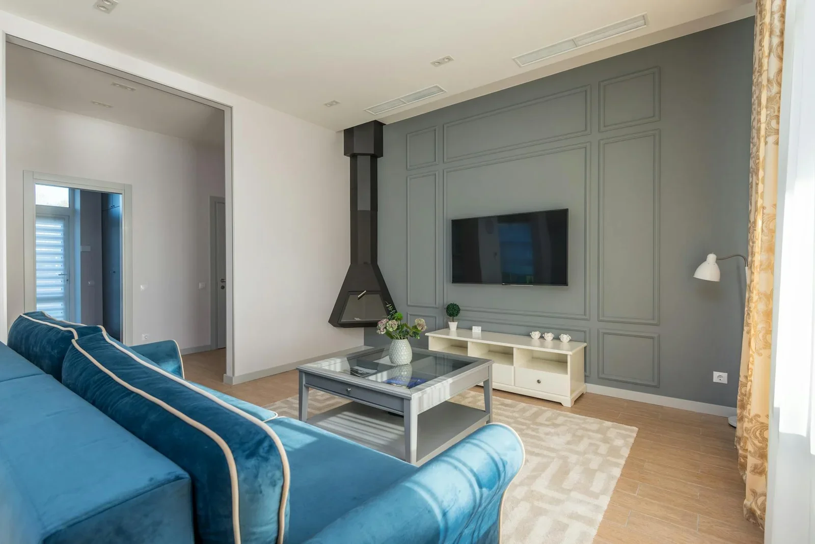 Sofa xanh dương kết hợp tivi treo tường và decor tinh tế, kiến tạo phòng khách liền bếp 20m2 sang trọng. | Thiết kế nội thất 24