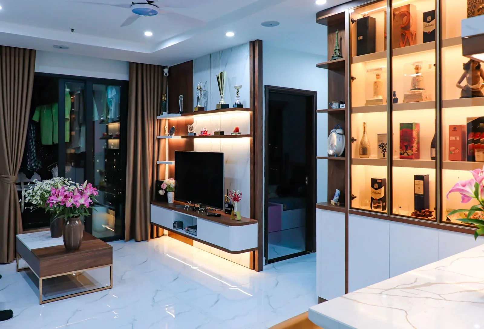 Sleek modern living room with illuminated shelves, TV unit, | Thiết kế nội thất 24