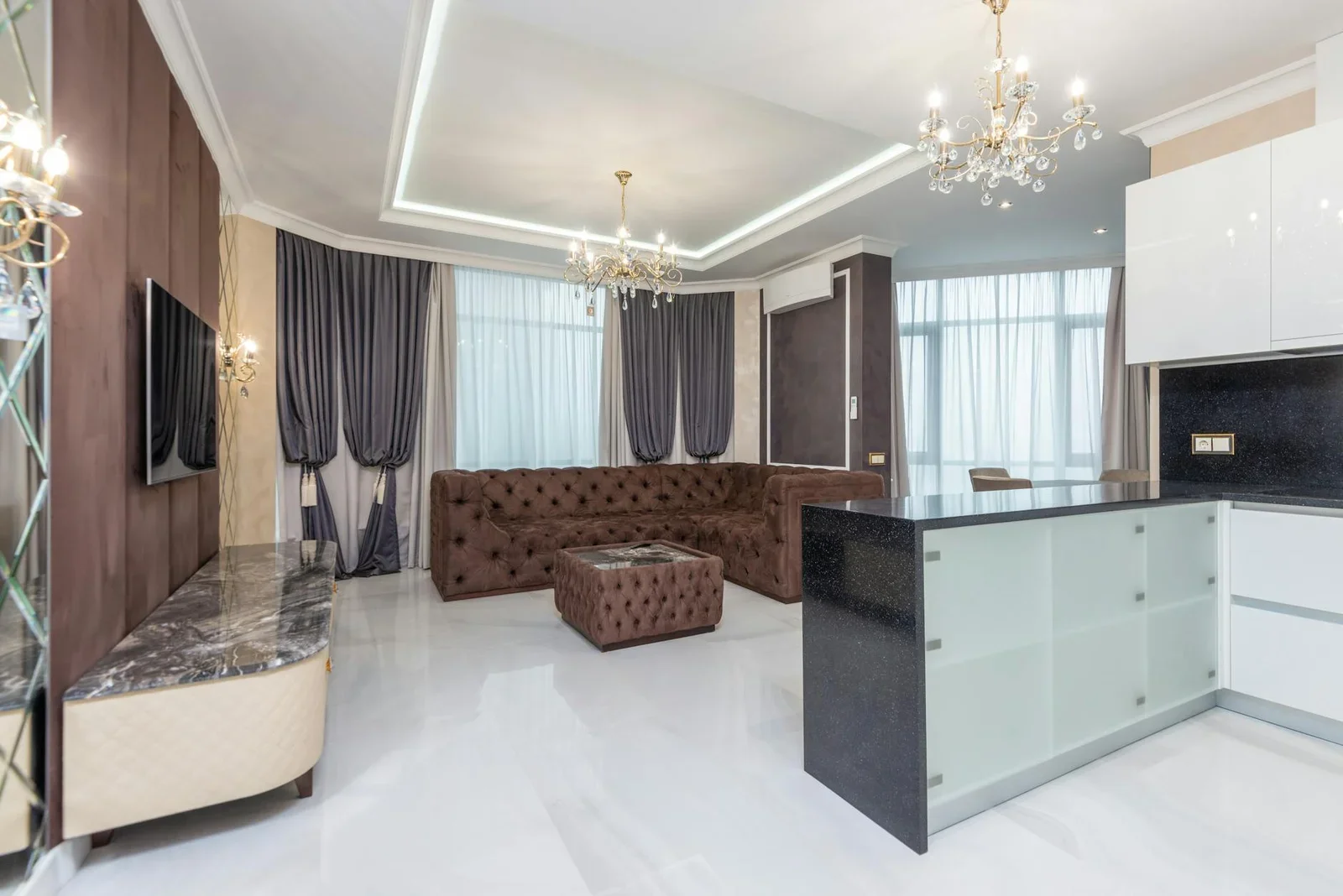 Đèn chùm sang trọng chiếu sáng bộ sofa êm ái, tôn lên vẻ đẹp đương đại cho không gian phòng khách liền bếp rộng mở. | Thiết kế nội thất 24