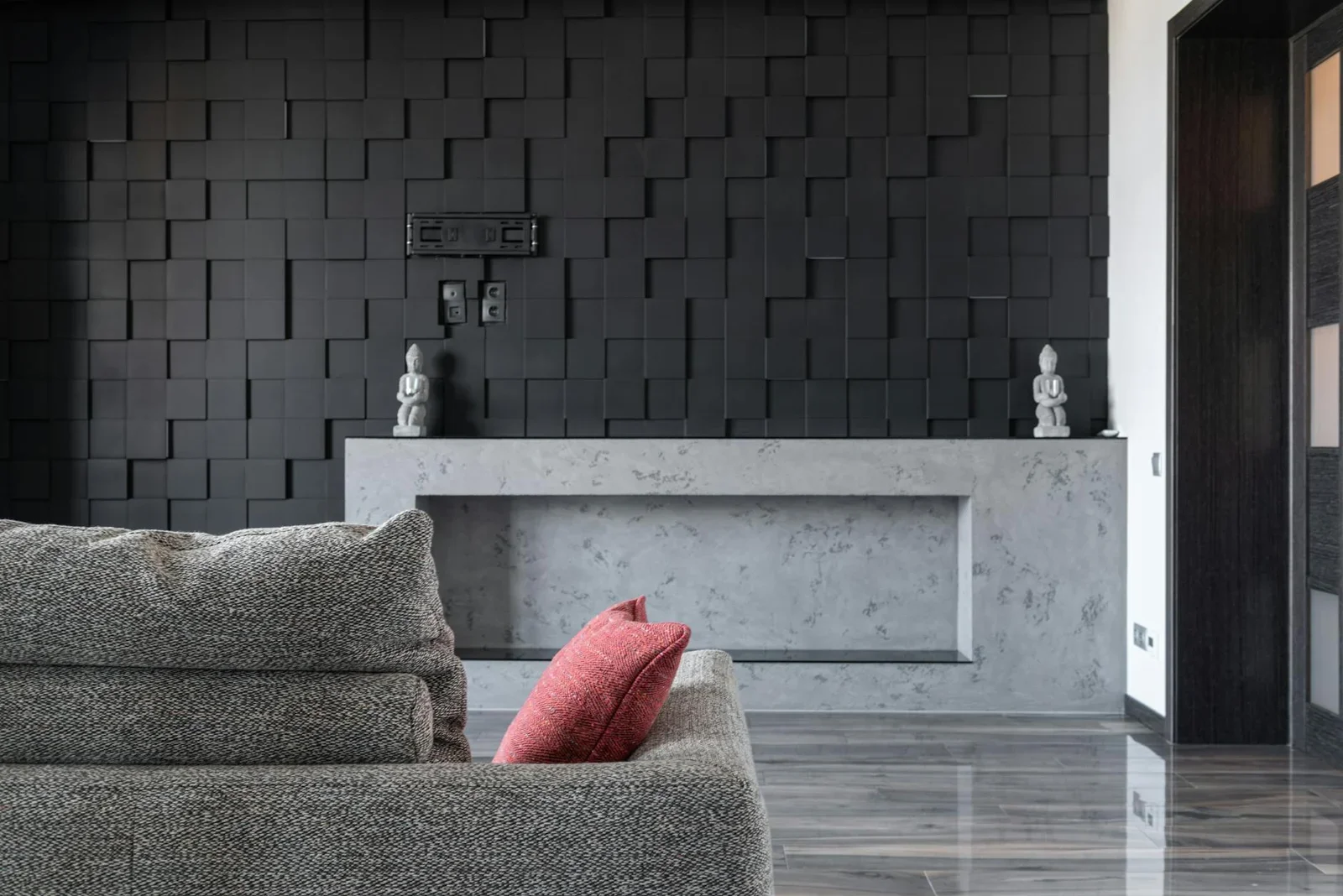 Sofa xám êm ái kề bên tường đen họa tiết nổi khối, ánh sáng dịu nhẹ tôn lên vẻ đẹp sang trọng và chiều sâu thị giác. | Thiết kế nội thất 24