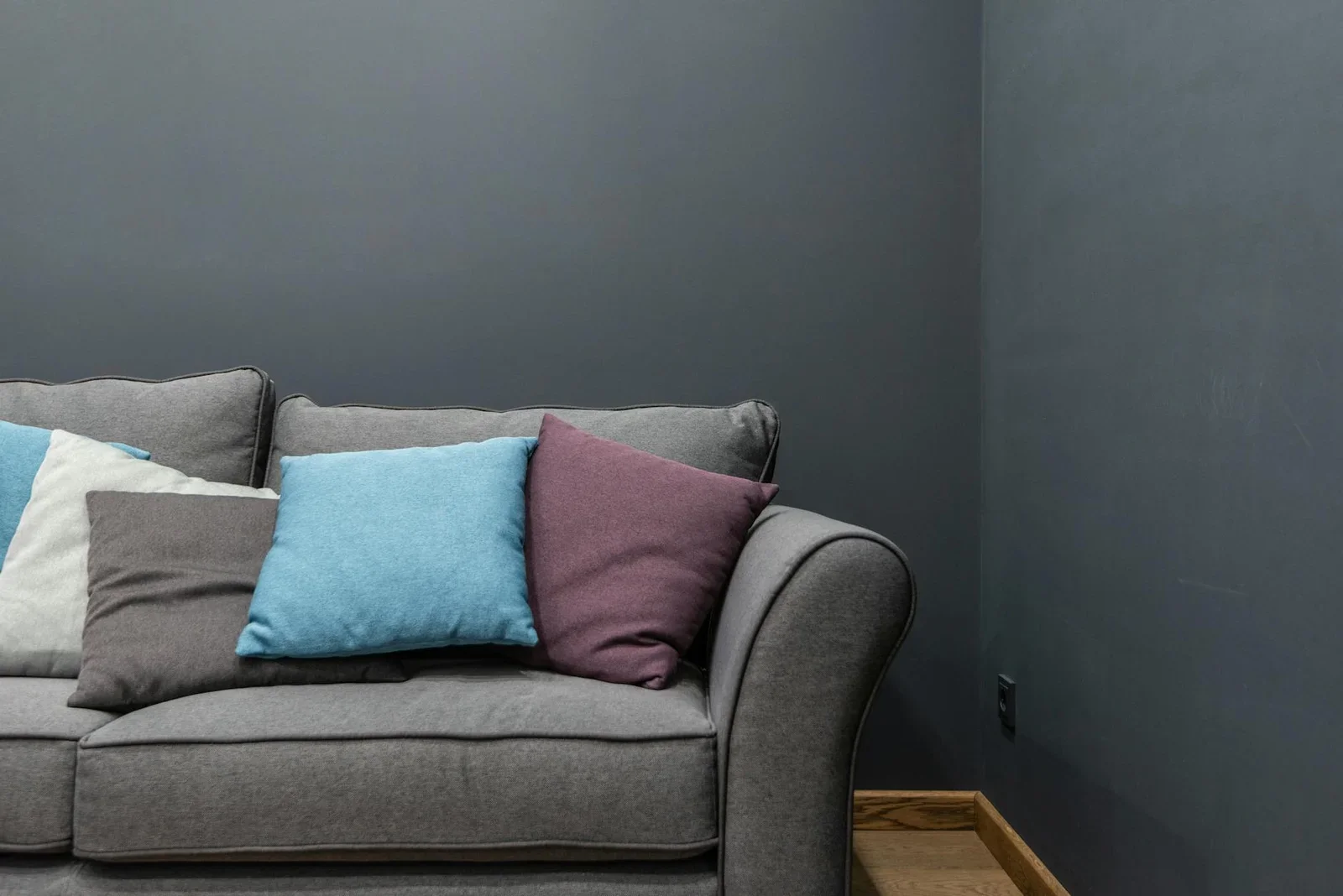 Ghế sofa xám mềm mại tựa tường, phối cùng gối tựa rực rỡ dưới ánh sáng tự nhiên tạo góc thư giãn thoáng đãng và lý tưởng. | Thiết kế nội thất 24