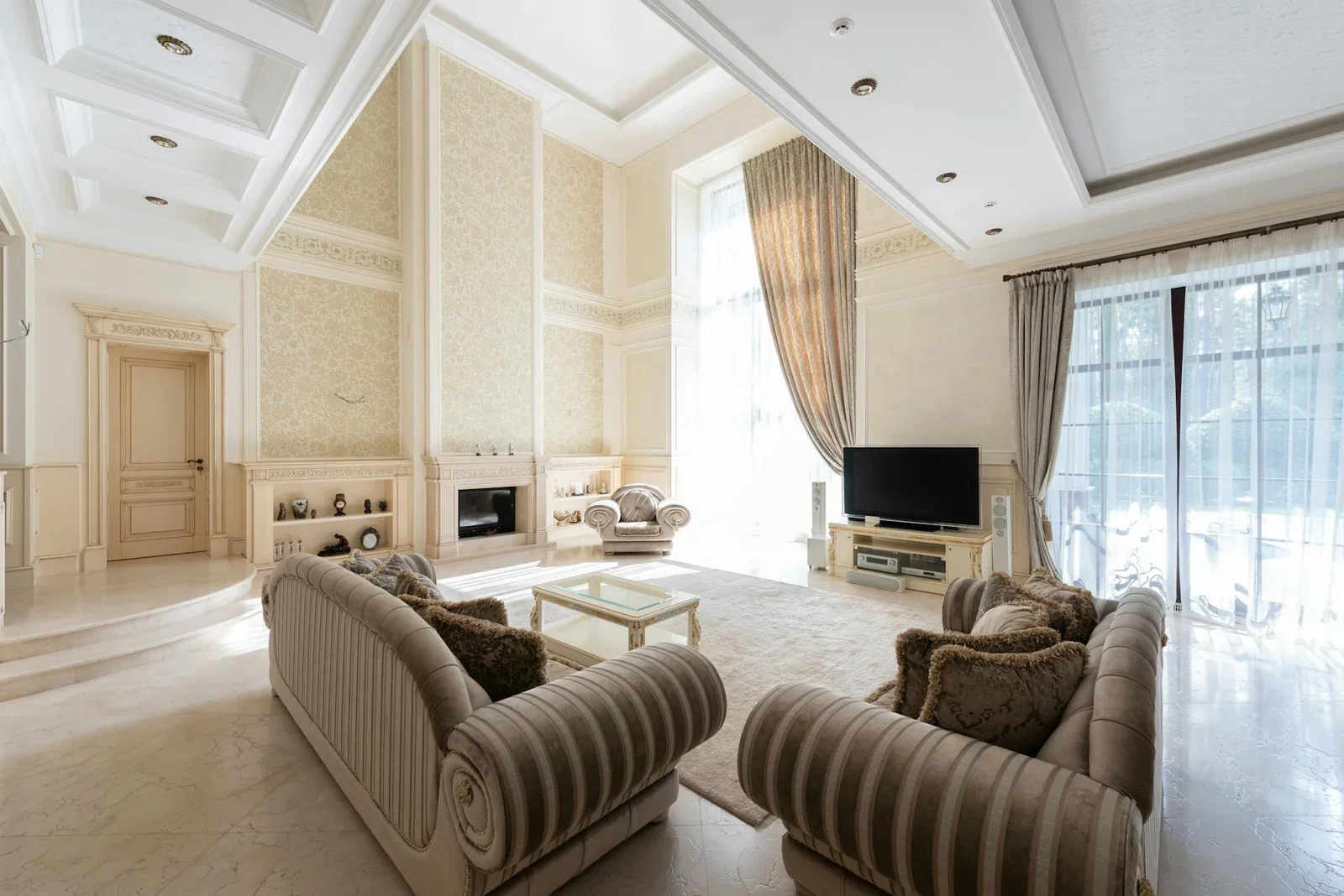 Không gian rộng rãi với bộ sofa đặt cạnh bàn trà trên thảm lớn, đối diện tivi và khung cửa sổ rèm lụa sang trọng. | Thiết kế nội thất 24