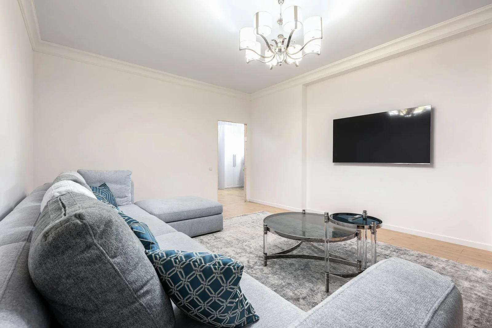Phòng khách bệt đương đại nổi bật với đèn chùm lấp lánh, kệ tivi thấp và bàn trà gỗ tạo điểm nhấn sang trọng. | Thiết kế nội thất 24