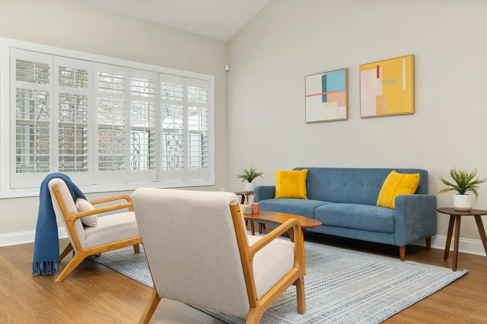 Phòng khách hiện đại nổi bật với sofa xanh, tranh trừu tượng cùng ánh sáng tự nhiên chan hòa qua khung cửa kính rộng. | Thiết kế nội thất 24