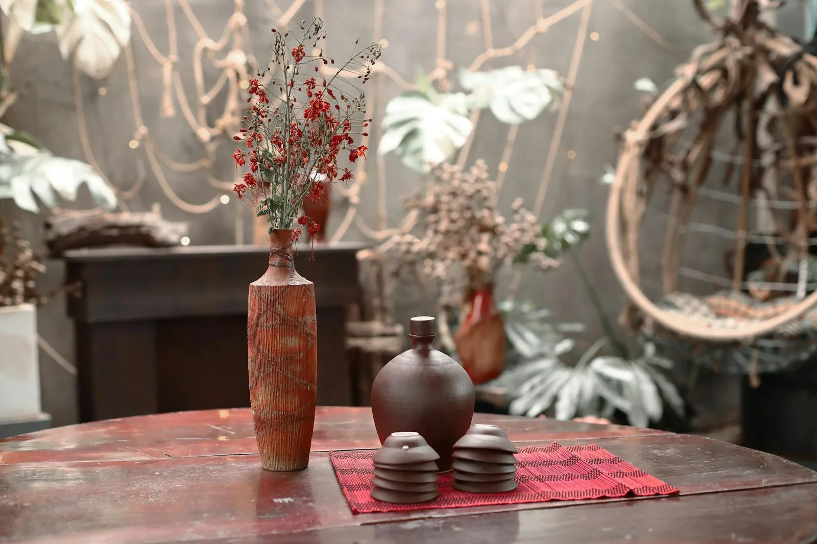 Bình gốm mộc mạc cùng cây xanh mướt đặt trên bàn gỗ, tạo góc nhỏ yên bình đậm chất Indochine cho phòng khách. | Thiết kế nội thất 24