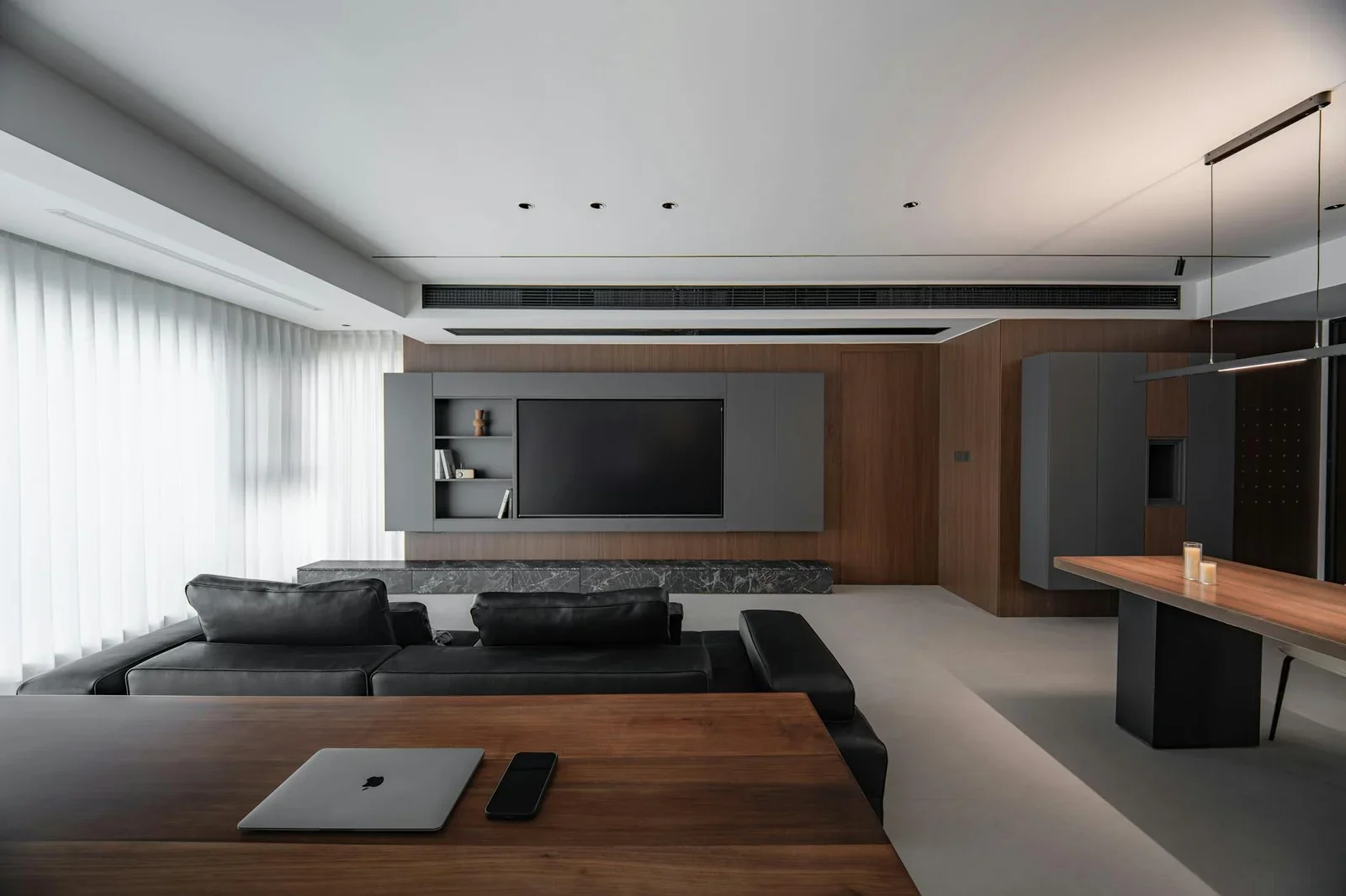 Phòng khách rộng rãi theo lối tối giản, phối hợp sofa đen hiện đại cùng bàn gỗ tự nhiên tạo điểm nhấn tinh tế. | Thiết kế nội thất 24