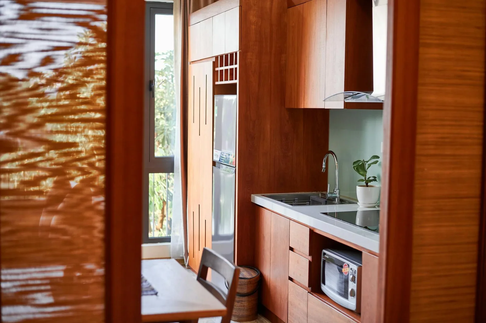 Bếp hiện đại với tủ gỗ tự nhiên và đường nét tối giản, tràn ngập ánh nắng tạo không gian nấu nướng thoáng đãng. | Thiết kế nội thất 24