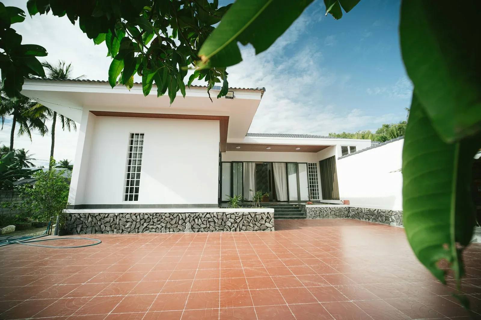 Sân thượng lát gạch mộc mạc dưới bầu trời xanh trong, nơi kết nối kiến trúc hiện đại với nhịp sống thư thái ngoài trời. | Thiết kế nội thất 24