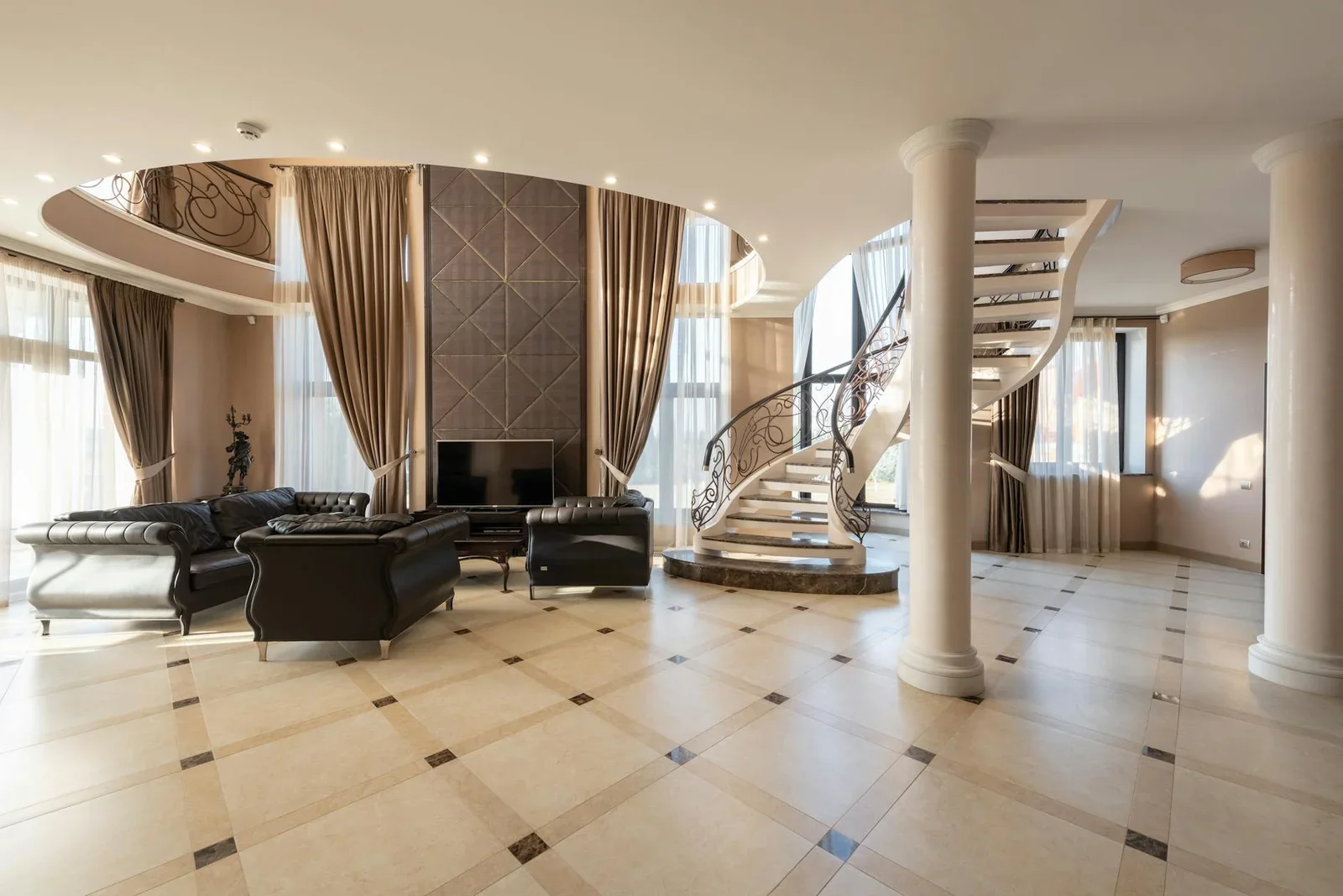 Hành lang rộng rãi phong cách cổ điển với hệ cột trụ, bộ sofa da êm ái cạnh cầu thang xoắn ốc. | Thiết kế nội thất 24