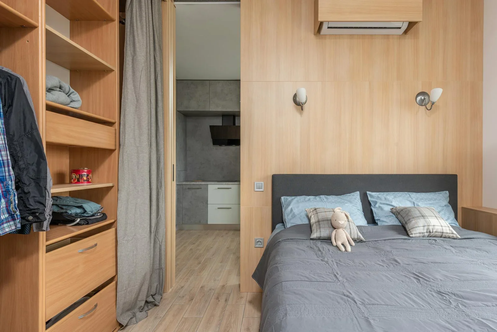 Giường ngủ êm ái đặt cạnh tủ quần áo ngăn nắp, kết nối liền mạch với khu bếp qua rèm cửa đón sáng tự nhiên. | Thiết kế nội thất 24