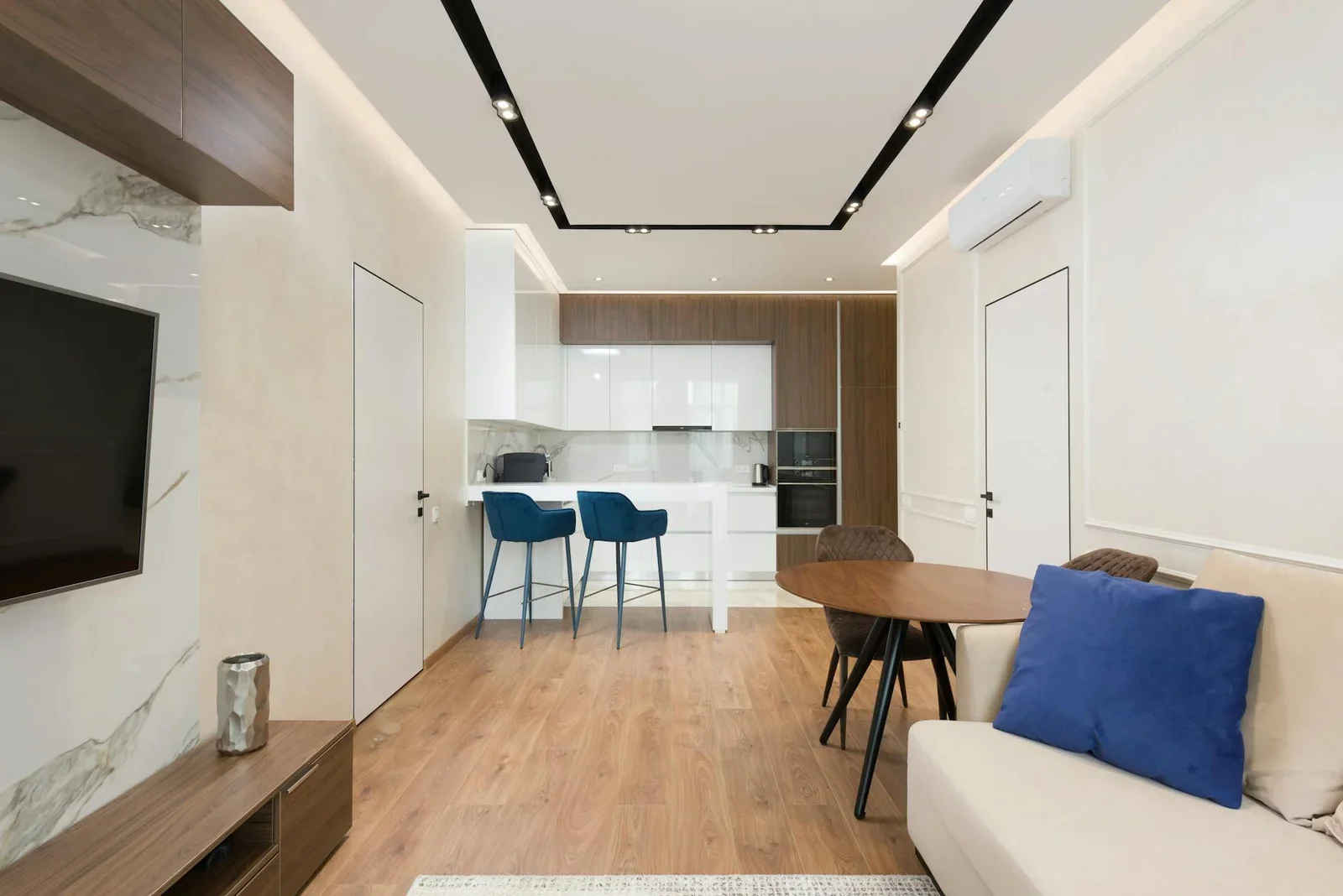 Ghế sofa êm ái kết hợp nội thất gỗ và tủ bếp trắng tạo sự liên kết hài hòa giữa phòng khách và bếp. | Thiết kế nội thất 24