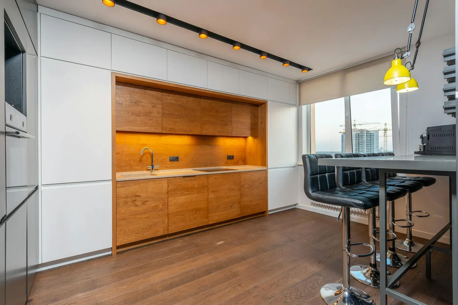 Bếp thiết kế tinh gọn với tủ gỗ ấm áp, ghế quầy bar tiện nghi và cửa kính lớn đón nắng tự nhiên. | Thiết kế nội thất 24
