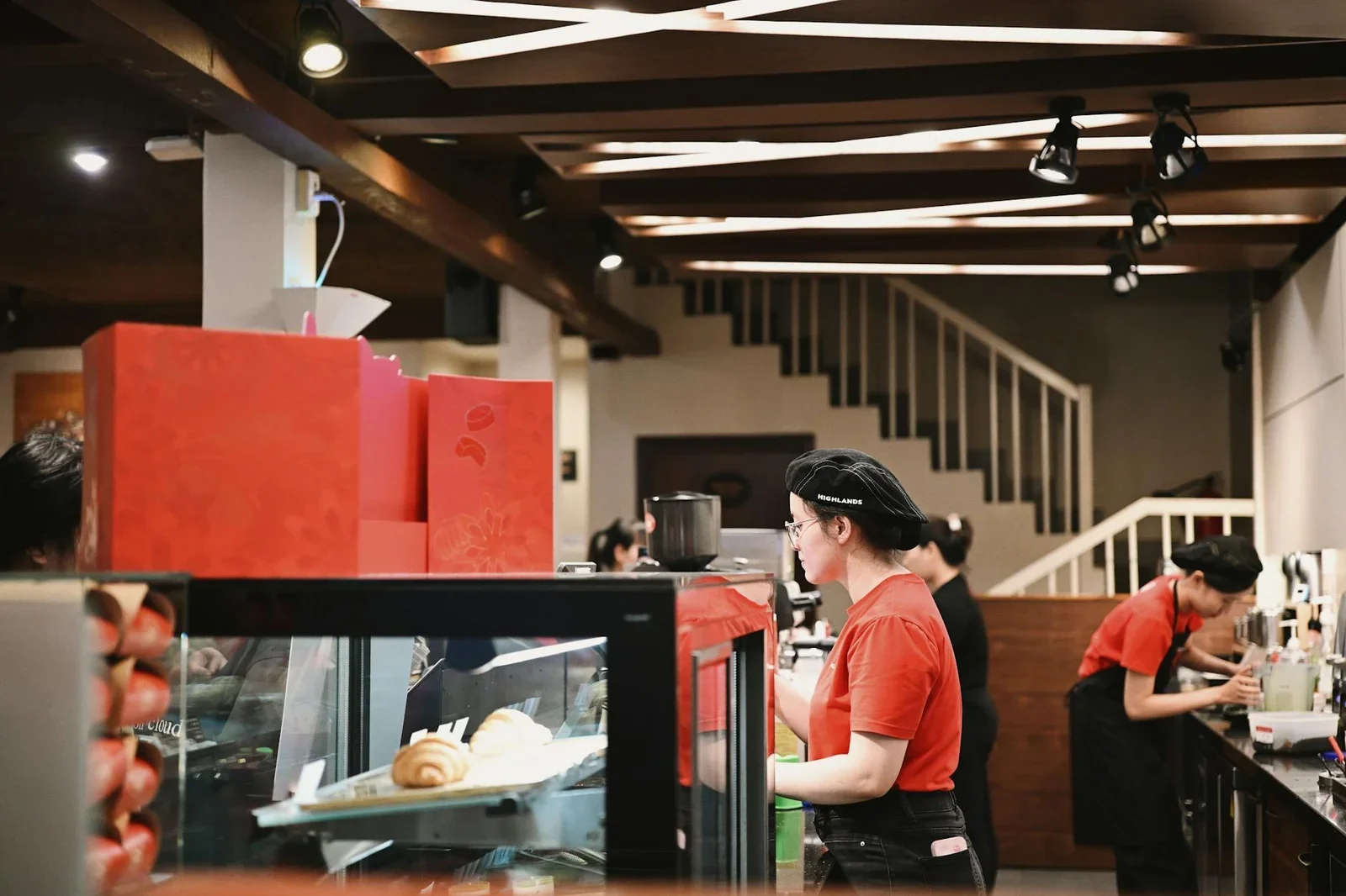 Khu pha chế nhộn nhịp cùng barista trong trang phục đỏ, được bố trí khoa học nhằm tối ưu quy trình vận hành cho quán cafe. | Thiết kế nội thất 24