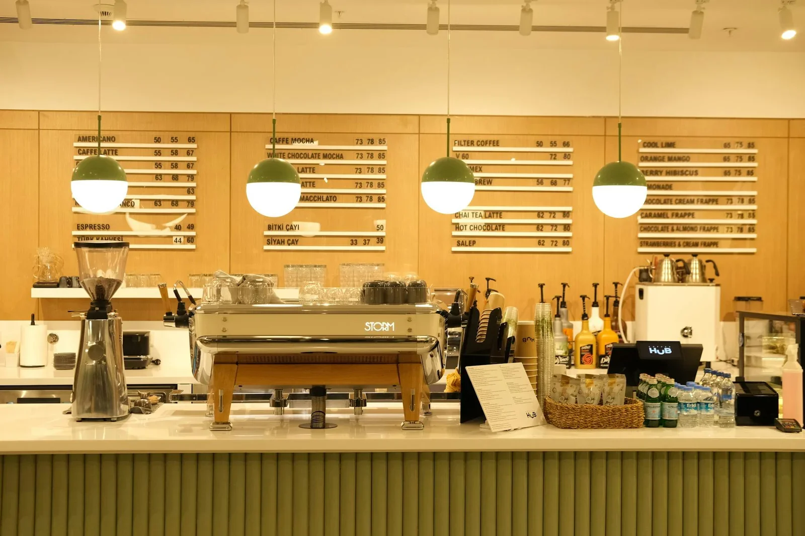 Quầy bar hiện đại tích hợp máy pha cùng bảng menu rõ nét, được chiếu sáng ấm áp để tạo điểm nhấn thu hút cho quán. | Thiết kế nội thất 24