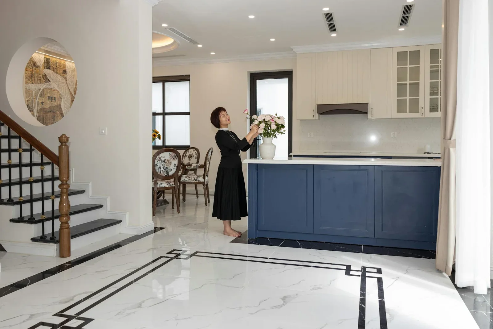 Khu bếp mở thông thoáng với thiết kế hiện đại, điểm xuyết nét ấm cúng từ lọ hoa tươi mang lại sự thân thuộc. | Thiết kế nội thất 24