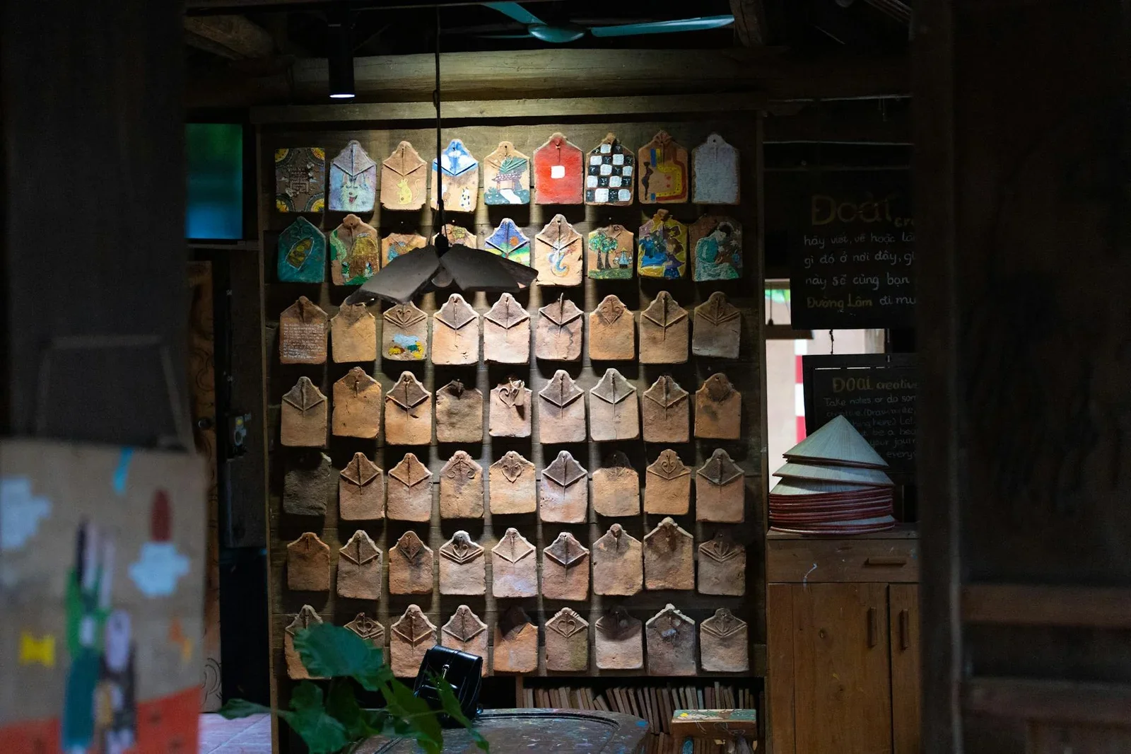 Không gian quán mộc mạc với tranh truyền thống và đồ trang trí thủ công, gợi ý tuyệt vời cho shophouse kinh doanh. | Thiết kế nội thất 24