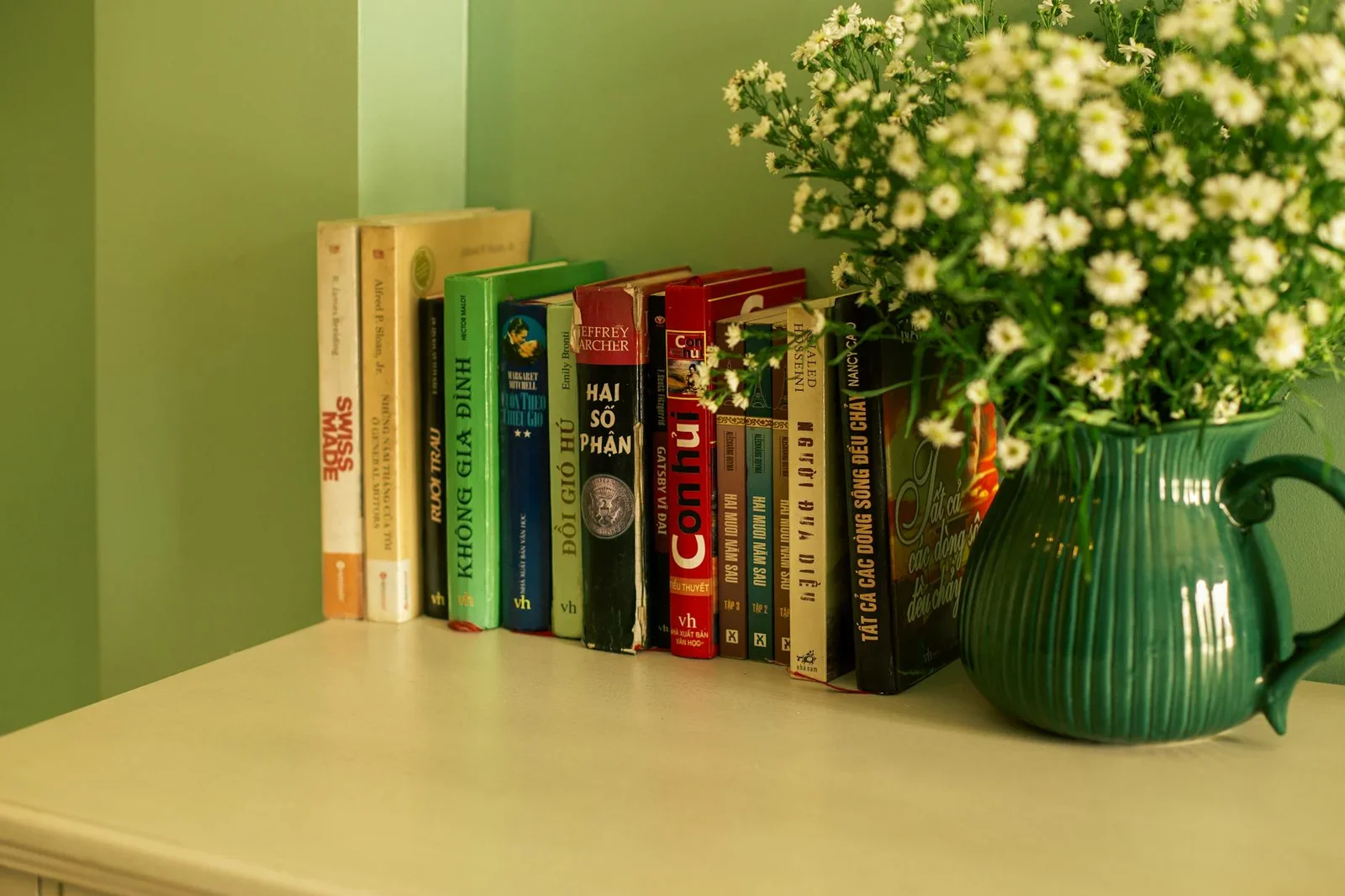A cozy bookshelf with various books next to a flower vase in | Thiết kế nội thất 24