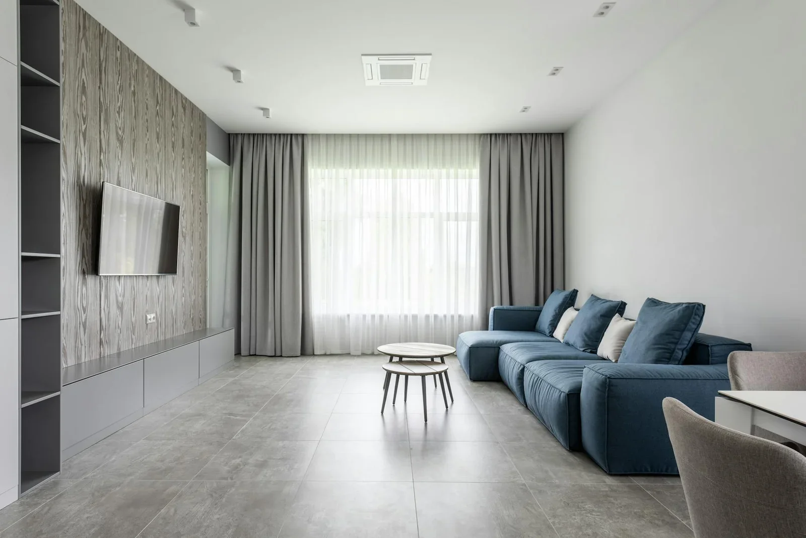 Phòng khách rộng rãi tràn ngập ánh sáng tự nhiên, nổi bật với bộ sofa xanh dương êm ái cùng gối tựa tạo cảm giác thư giãn tuyệt đối. | Thiết kế nội thất 24