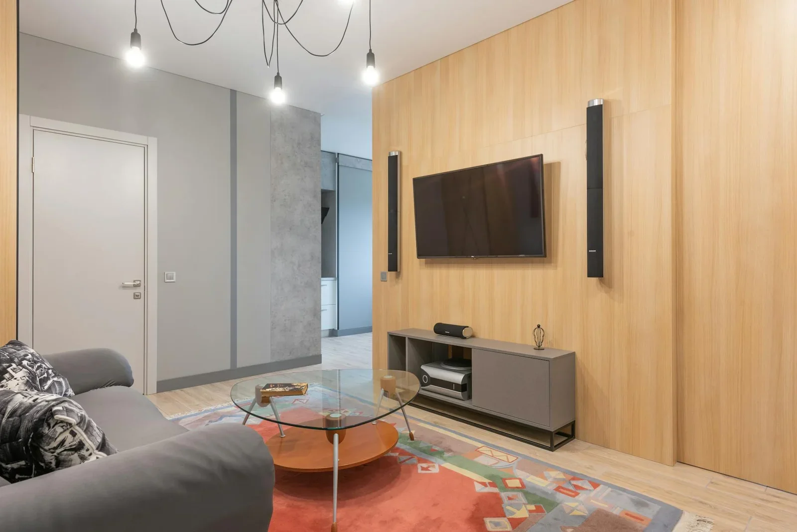Ghế sofa êm ái đi kèm bàn trà kính và đèn chùm nghệ thuật, thảm trang trí tạo điểm nhấn độc đáo cho phòng khách đương đại. | Thiết kế nội thất 24