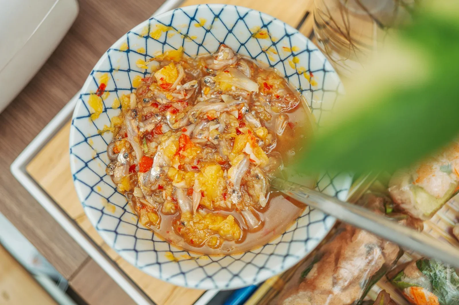Bát gốm hoa văn đựng nước chấm đỏ tươi trên bàn gỗ, tôn vinh chất liệu thủ công và nghệ thuật bày biện. | Thiết kế nội thất 24