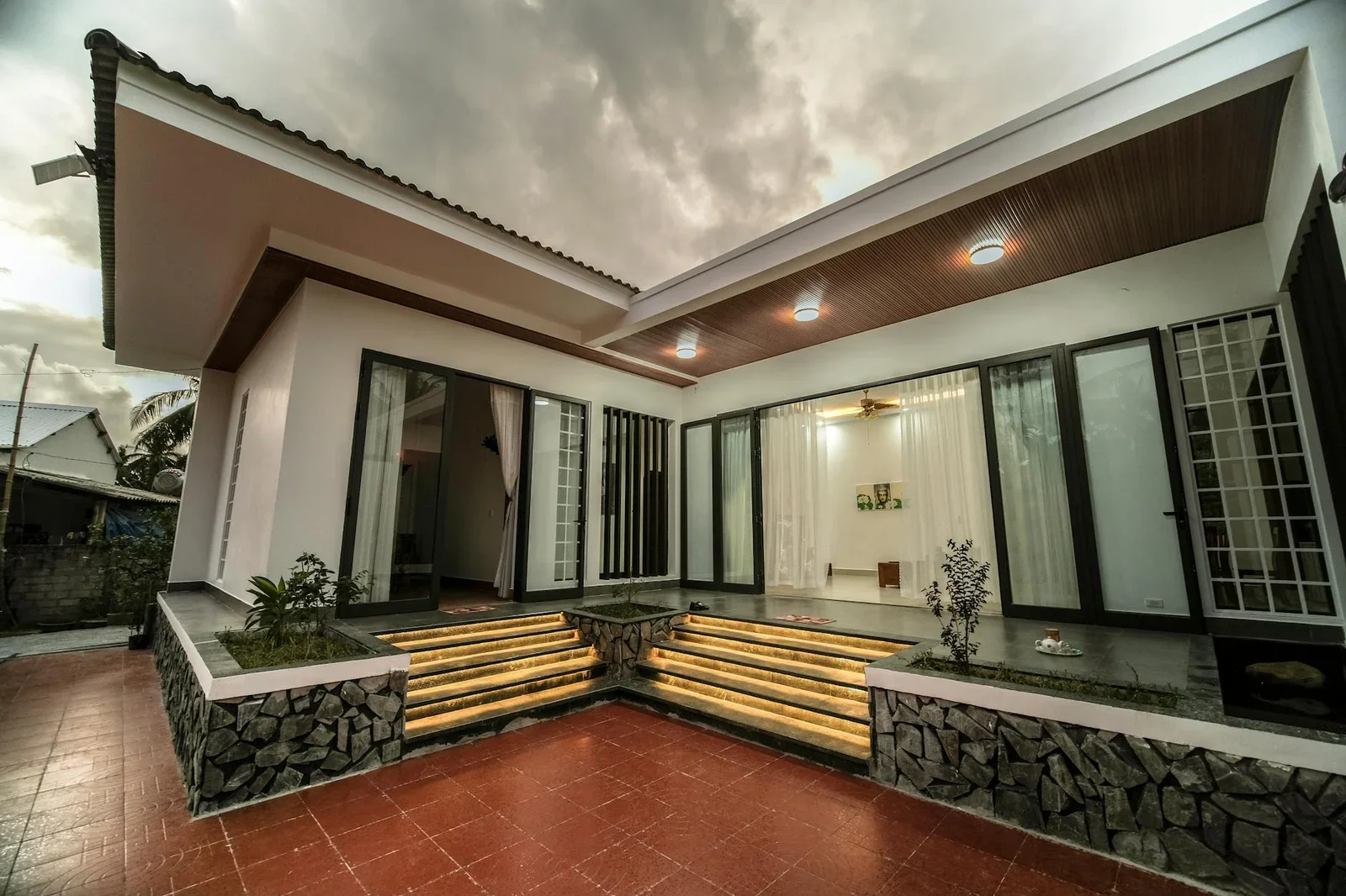 Thiết kế nhà một tầng hiện đại với cửa kính lớn, ánh sáng đèn bậc thang tạo điểm nhấn ấm áp giữa tiết trời âm u. | Thiết kế nội thất 24