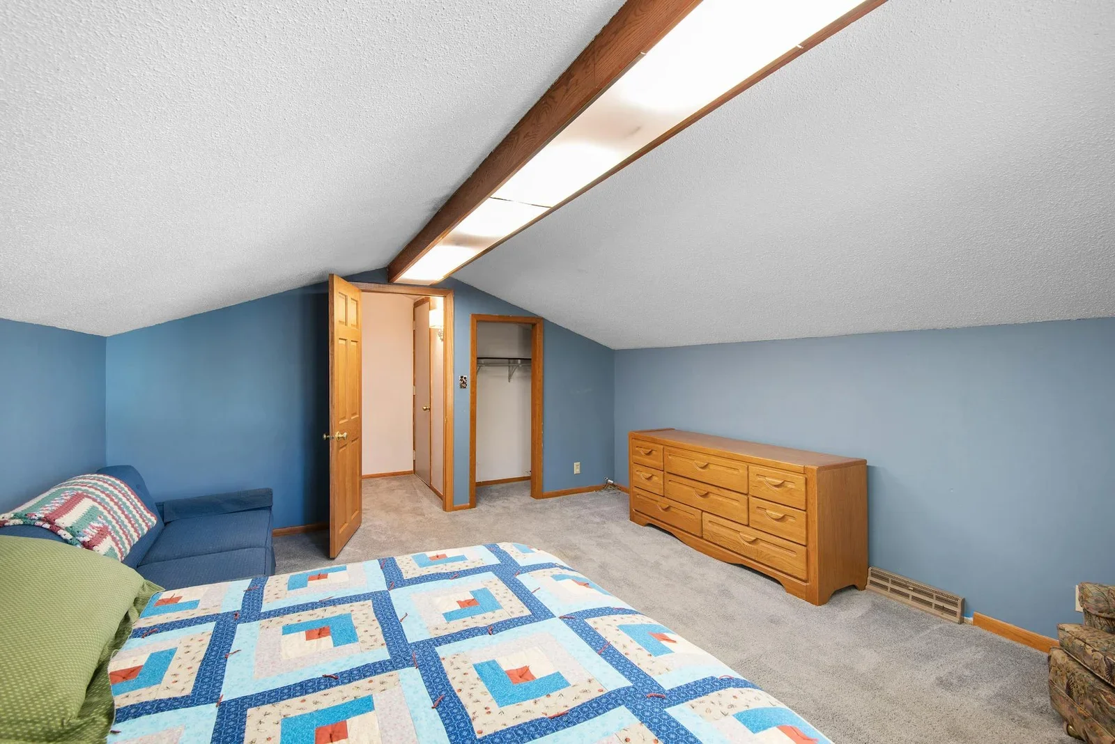 Phòng ngủ căn hộ Duplex gác mái tràn ngập ánh sáng, phối hợp chăn ga sắc màu cùng tủ gỗ tự nhiên tạo không gian nghỉ ngơi ấm cúng.