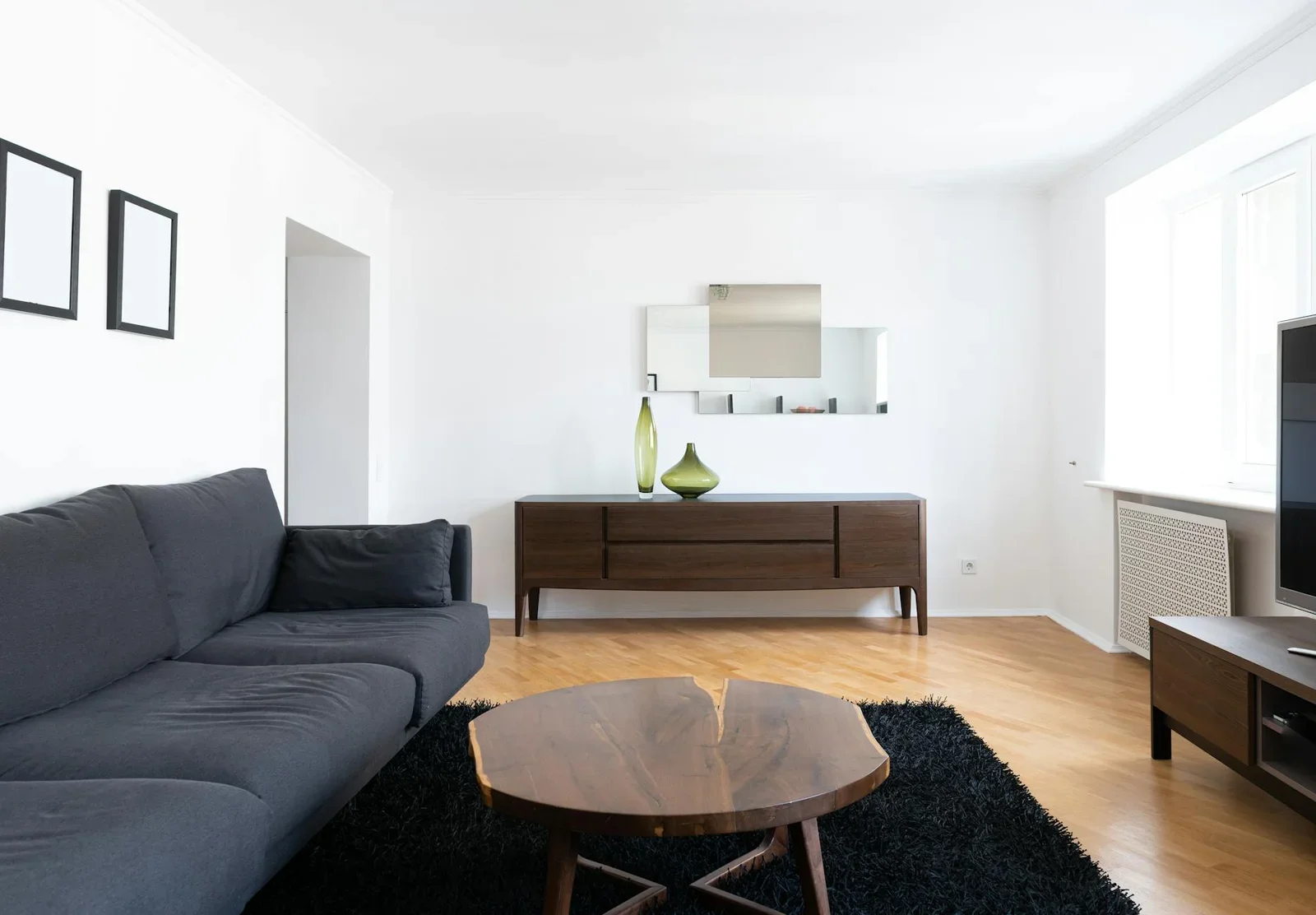 Ngôi nhà tràn ngập ánh sáng với ghế sofa, bàn gỗ trên thảm và tủ trang trí lọ hoa, mang lại cảm giác bình yên. | Thiết kế nội thất 24