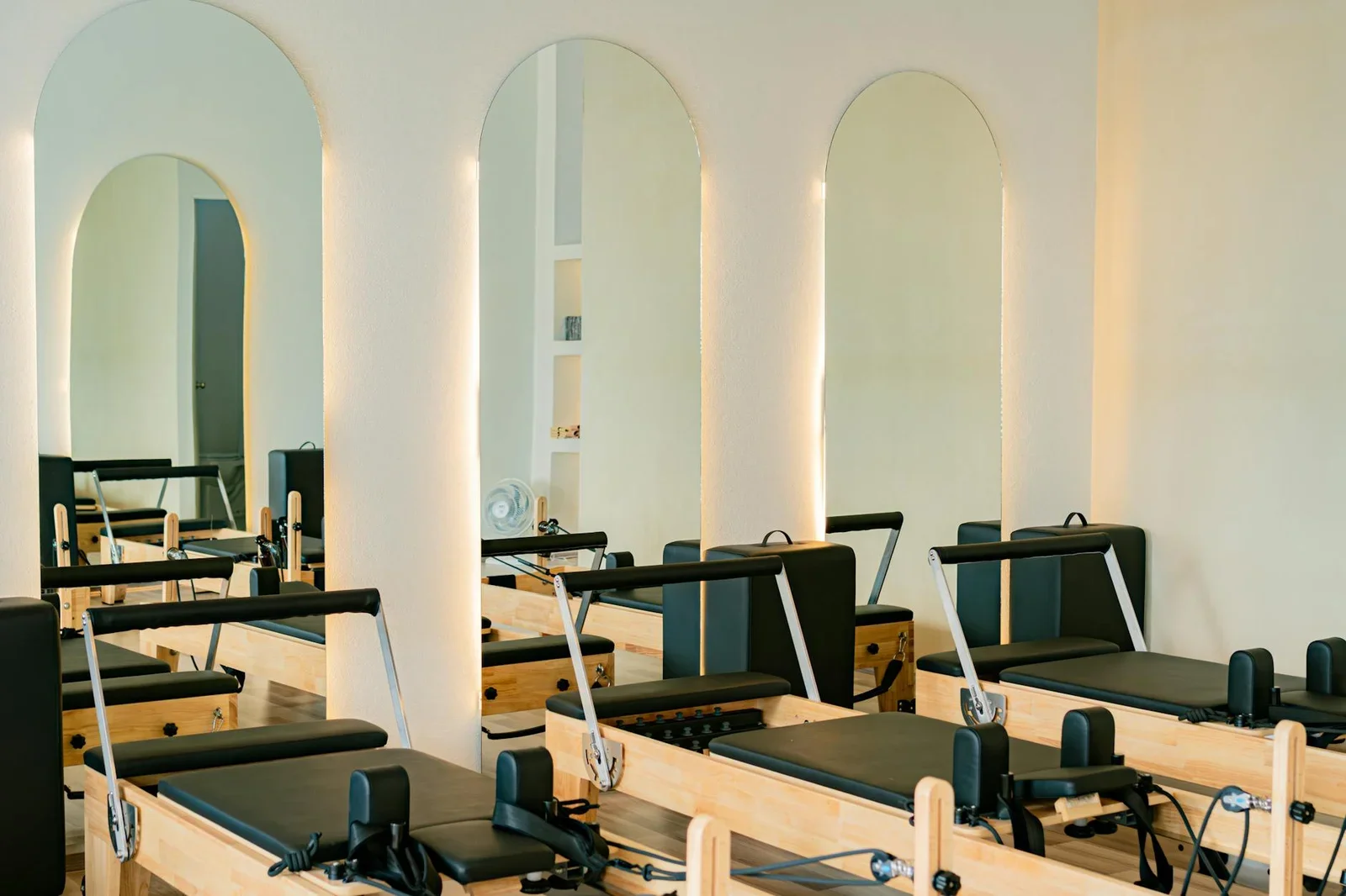 Phòng tập tại gia phong cách tối giản với máy reformer hiện đại, tường gương mở rộng không gian và ánh sáng tự nhiên tràn ngập. | Thiết kế nội thất 24