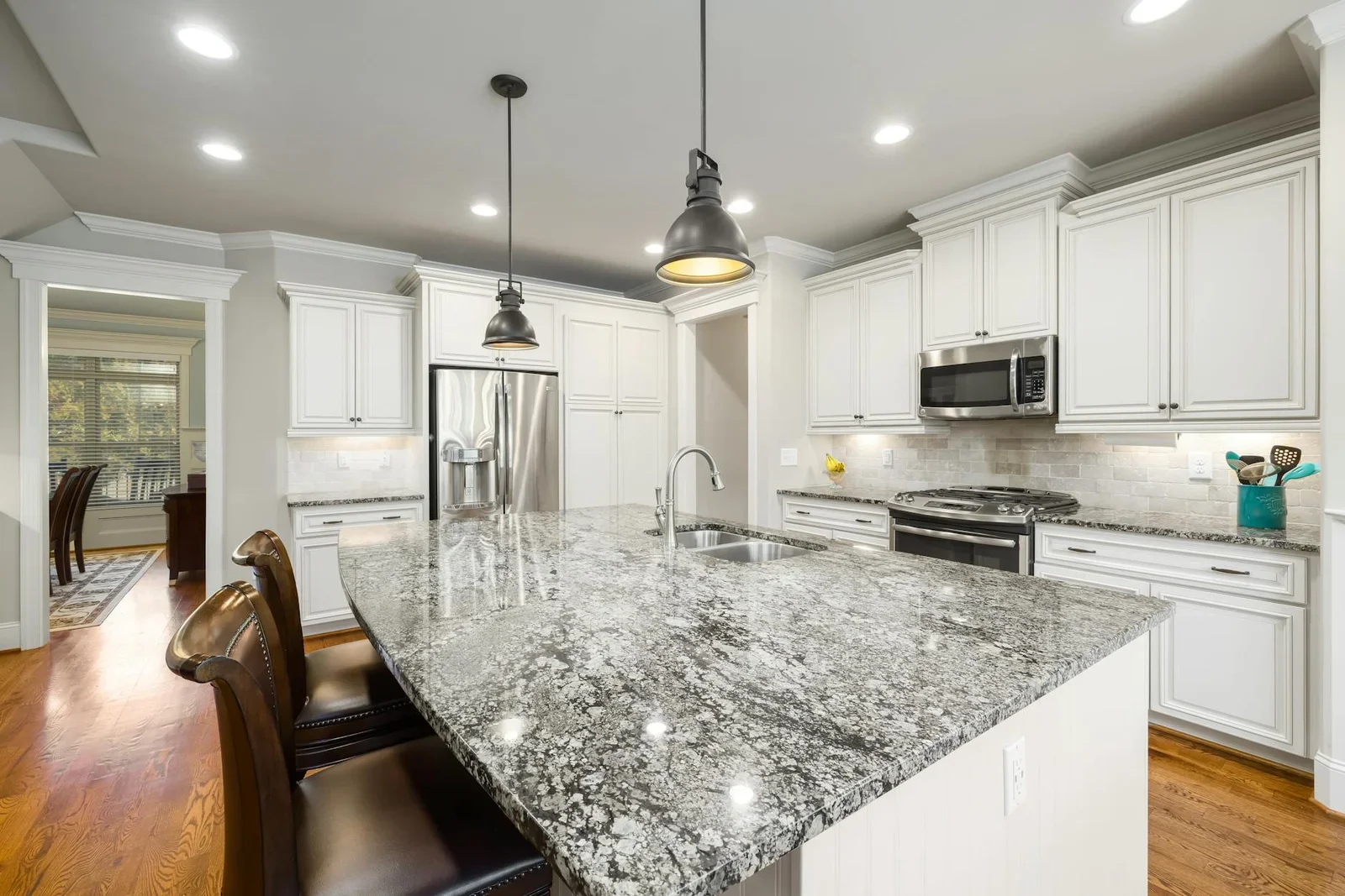Không gian bếp hiện đại rộng rãi với hệ tủ trắng sang trọng, đảo bếp đá granite và thiết bị inox cao cấp. | Thiết kế nội thất 24