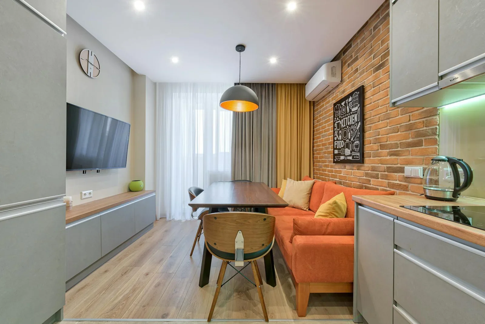 Nội thất căn hộ cá tính với tường gạch mộc, sofa cam nổi bật và đồ gỗ tự nhiên, kiến tạo phòng khách trẻ trung đầy sức sống. | Thiết kế nội thất 24
