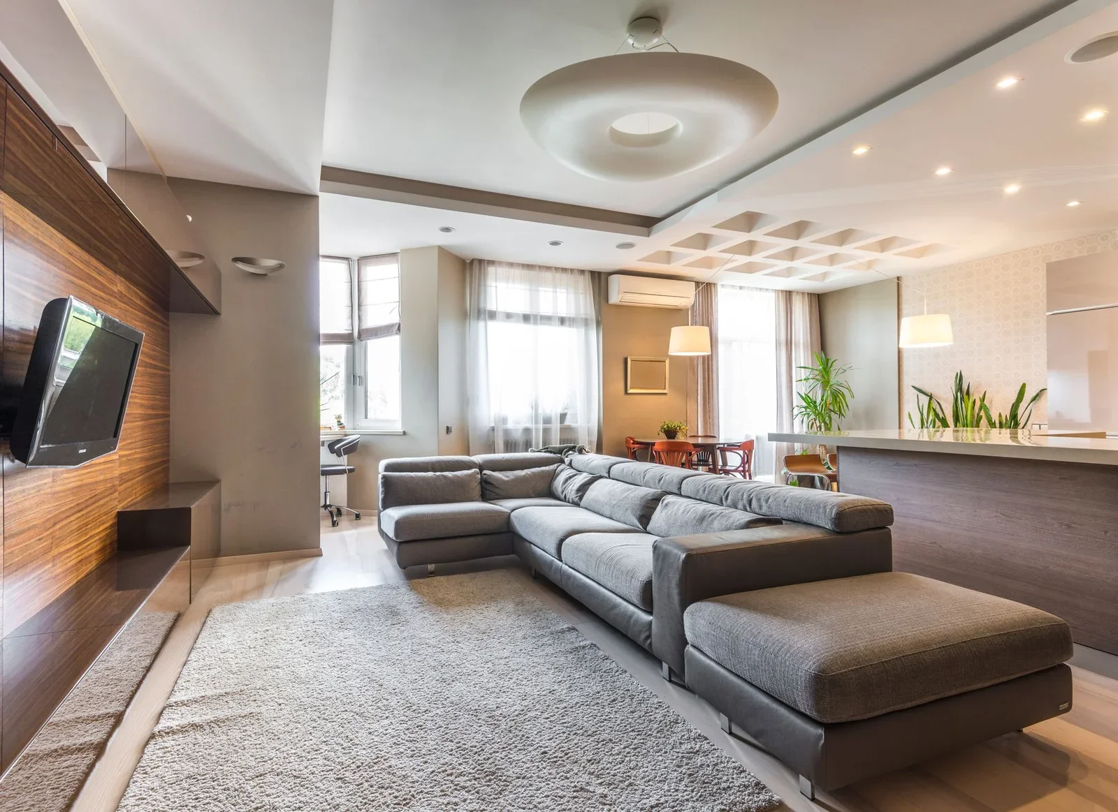 Phòng khách đương đại rộng rãi nổi bật với sofa xám liền mạch và thiết kế bếp mở, tối ưu công năng và sự kết nối không gian. | Thiết kế nội thất 24