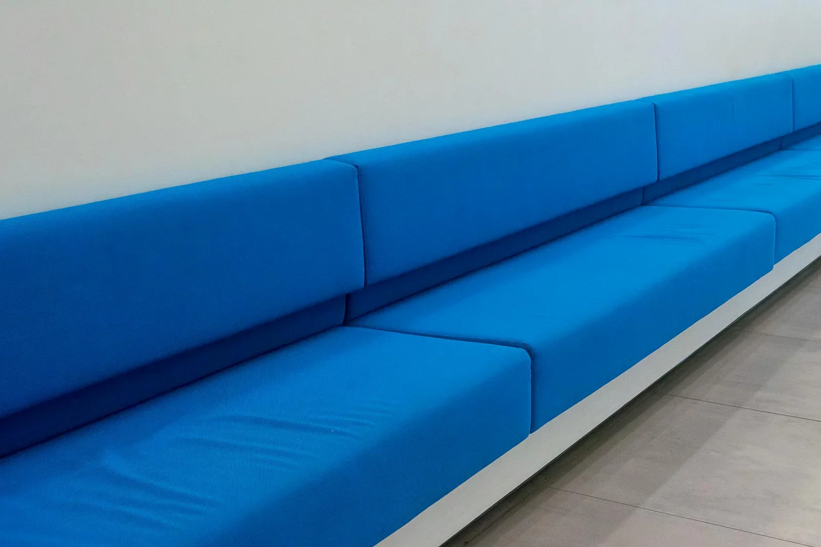 Ghế sofa dài tông xanh dương kê sát tường trắng, phong cách tối giản tạo khu chờ thoải mái và sang trọng dành cho phụ huynh. | Thiết kế nội thất 24