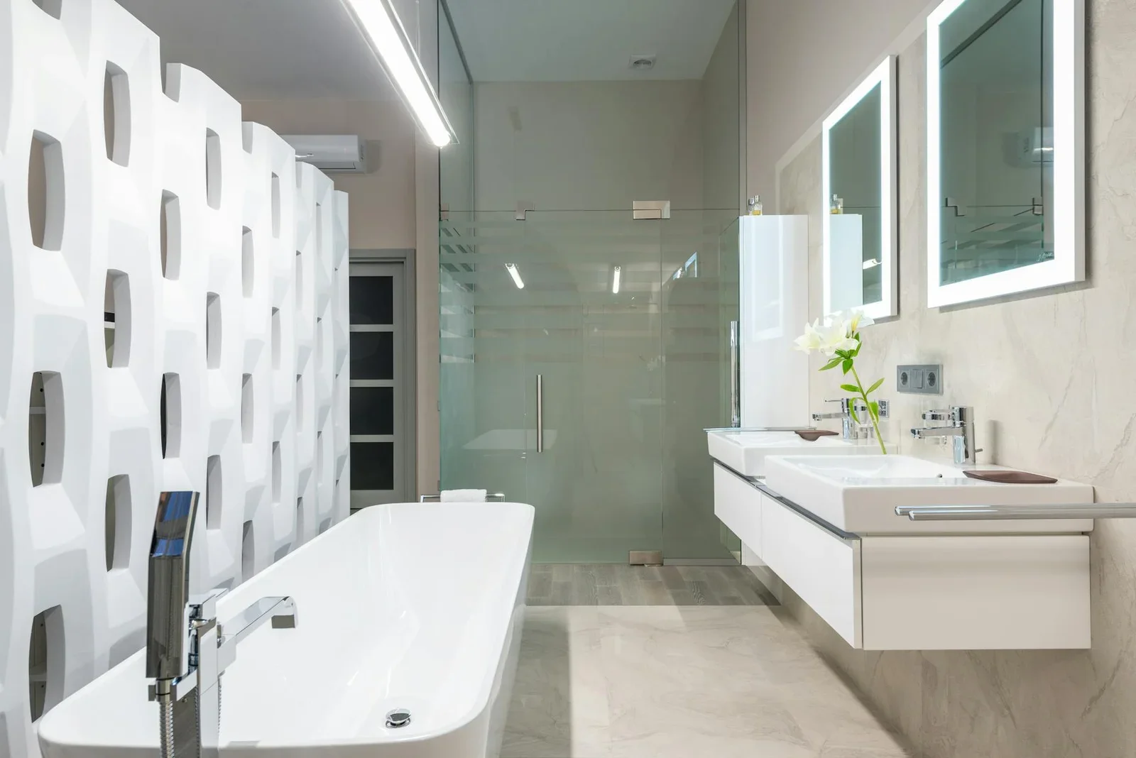 Bồn tắm trắng đặt cạnh vách ngăn trang trí, kết hợp lavabo và gương lớn trong phòng tắm sáng sủa có cabin kính. | Thiết kế nội thất 24