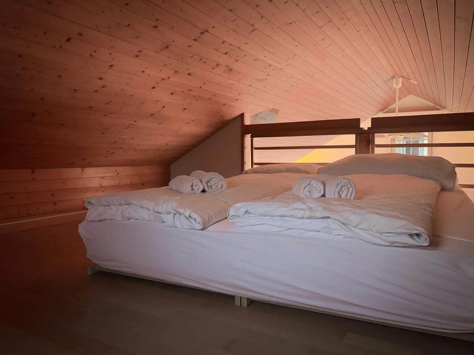 Phòng ngủ gác mái duplex ấm cúng với trần gỗ, ga giường tươi mới và ánh sáng dịu nhẹ tạo cảm giác thư thái. | Thiết kế nội thất 24